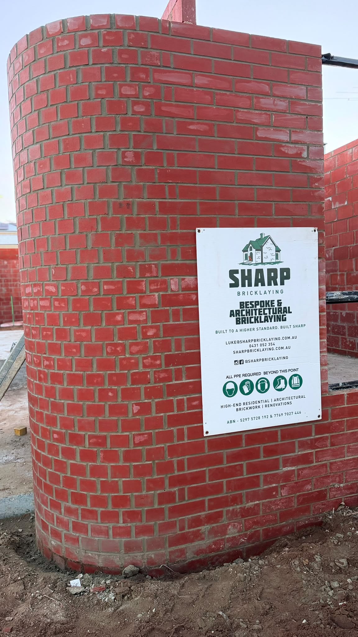 Curved red brick water tank with Sharp Bricklaying signage fixed to it